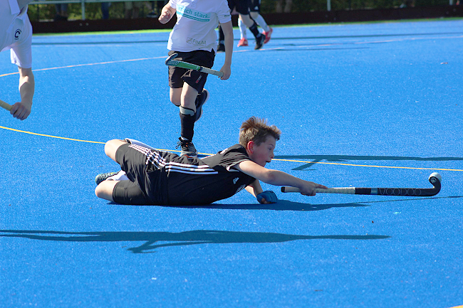 A hocey player dives on the blue pitch